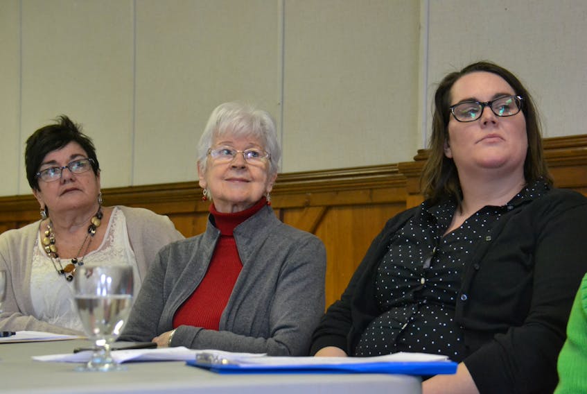 Jillian Kilfoil, right, Marie Burge, centre, and Marcia Carroll listen to one of the speakers Tuesday as they call for an update to the Employment Standards Act.