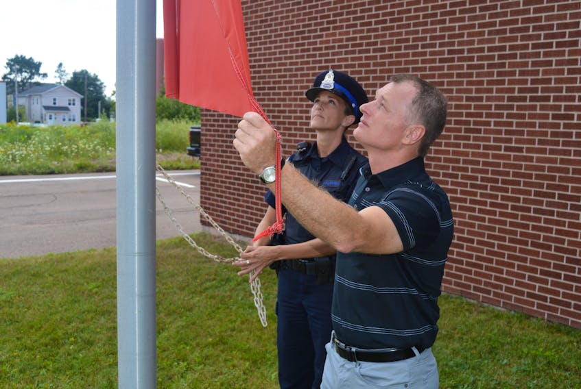 Charlottetown Deputy Police Chief Brad MacConnell and Const. Melissa Craswell lower the flag at police headquarters to half-mast following the shooting in Fredericton, N.B., Friday that left four people dead, including two police officers.