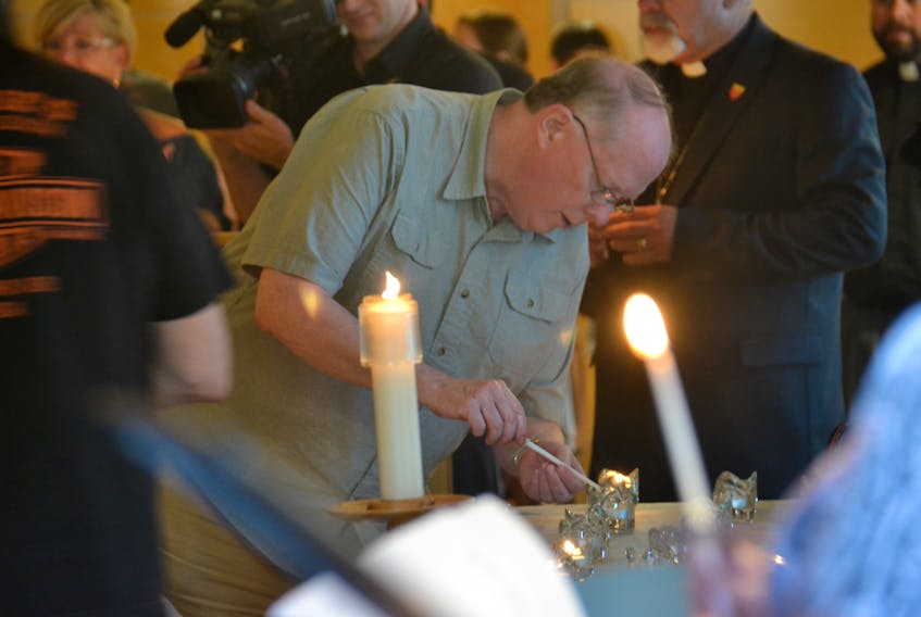Residents light candles at a vigil on Aug. 10, 2018 at Saint John the Evangelist Church. A shooting that morning claimed the lives of four individuals, including two police officers.