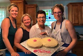 Kathy Kaufield, second from the right, displays a cake baked by volunteers involved with the #TellMe campaign. Kaufield, who lives in New Brunswick and is originally from Stratford, P.E.I., started the campaign to raise awareness about how mammograms can miss tumours from women with dense breasts.