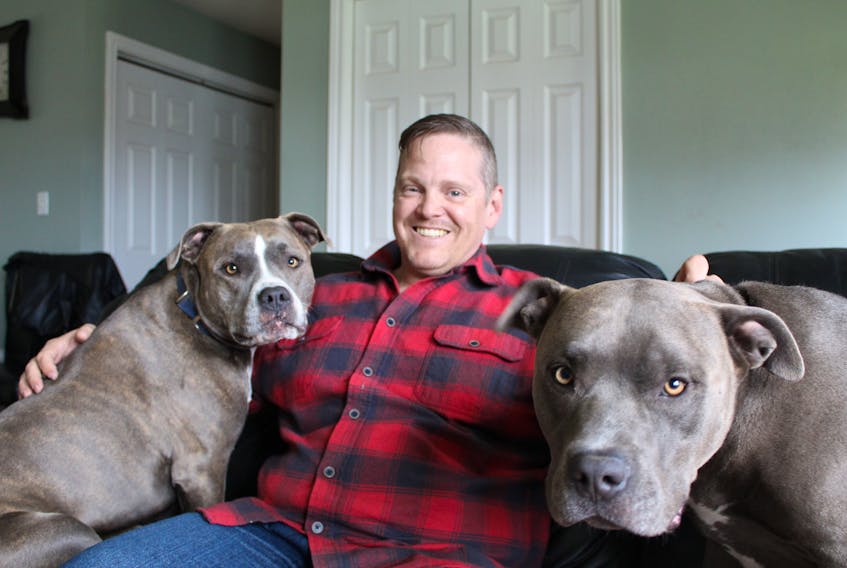Retired Warrant Officer Trent Vail enjoys a moment with his dogs, Gimley and Tig, at his Charlottetown home.
