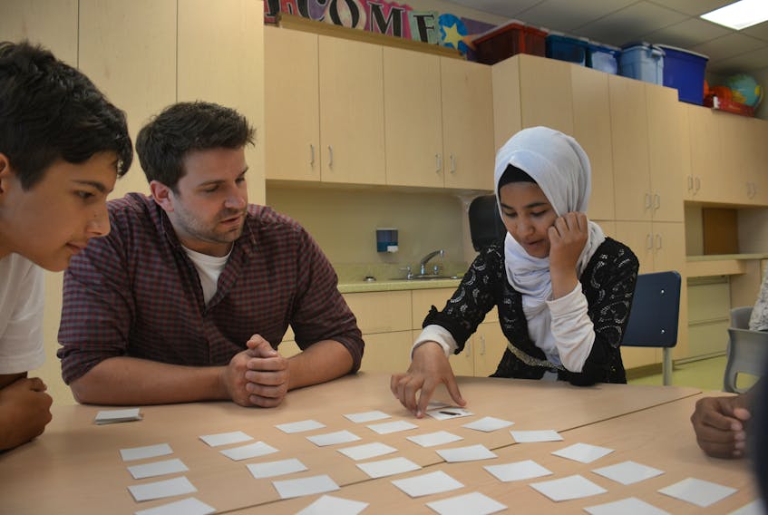 English as an additional language instructor Jeremy Hogan, centre, plays a card game teaching English with students German Ivkovich, left, and Baraa Alobaid at Spring Park Elementary School Thursday.