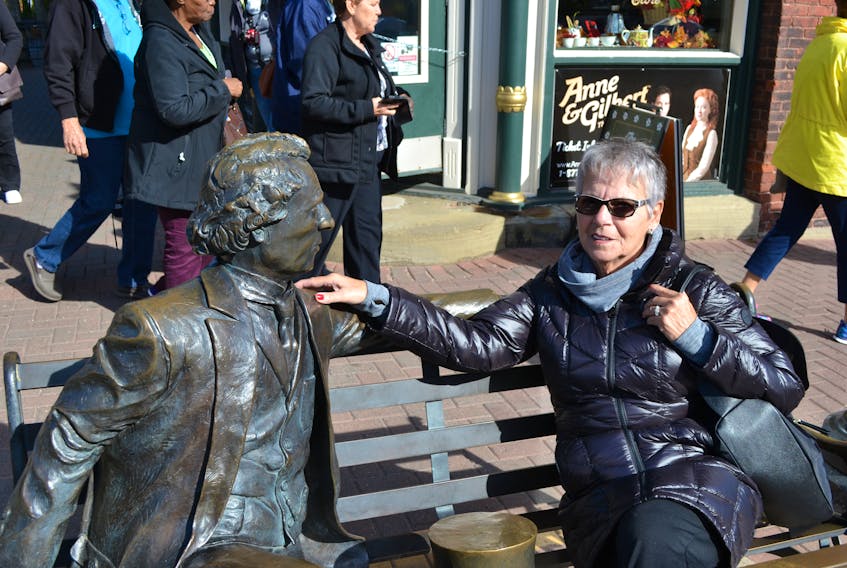 Louise Levac from Repentigny, Que., sits with the statue of John A. Macdonald while taking a break from exploring downtown Charlottetown. (Payton Jakubowski and Emily Doucette/Special to The Guardian)