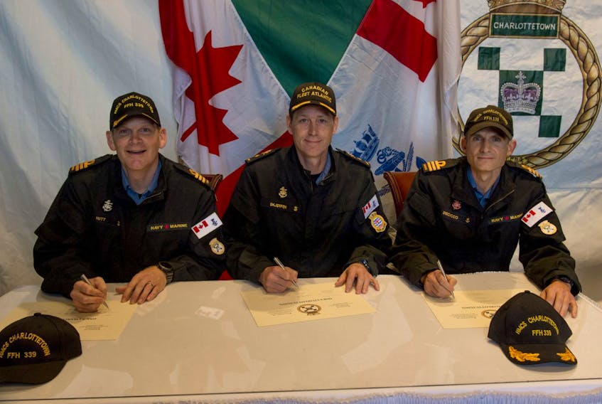 Commander Jeff Hutt, left, signs over command of HMCS Charlottetown to Commander Nathan Decicco, right, in a ceremony held recently in Kiel, Germany. The change-of-command certificate was overseen by the reviewing officer, Commodore Craig Skjerpen, who is Commander of Canadian Fleet Atlantic. SUBMITTED PHOTO