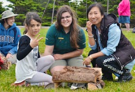 Parks Canada employee Hannah Aitken, centre, teaches seven-year-old Laura-Mae Hajjar, left, of Lebanon and Jennifer Zhang of China how to start a fire at Stanhope campground on June 16 during a Parks Canada Learn-to-Camp event.