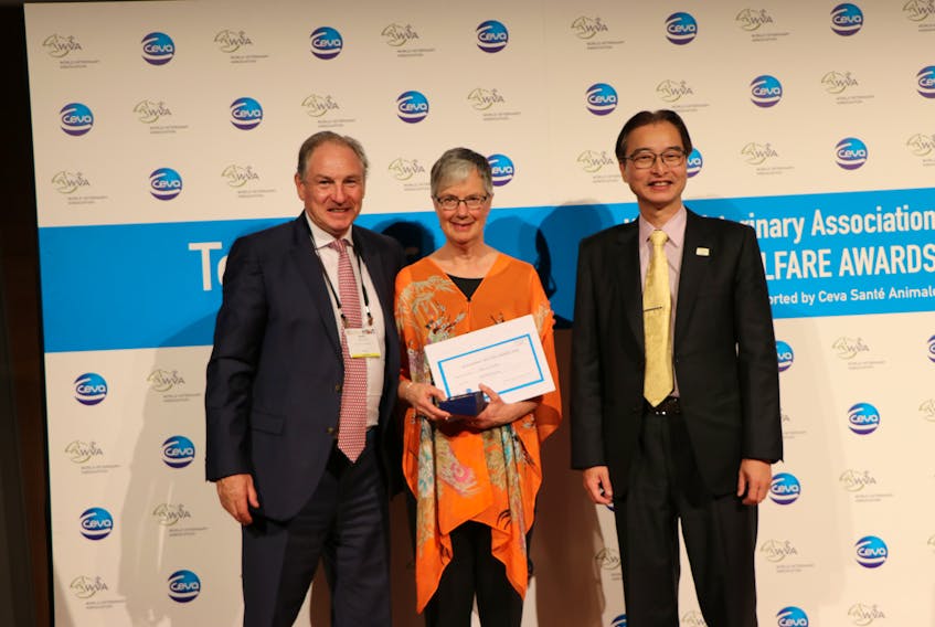 Alice Crook accepts her award from Martin Mitchell, left, of Ceva Santé Animale, and Johnson Chiang, right, president of the World Veterinary Association.