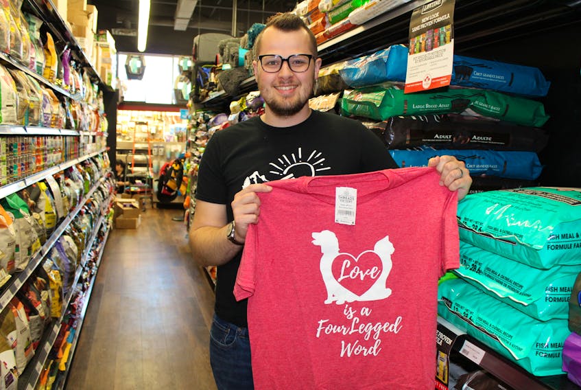 Kieran Atkinson displays one of his Threads for Paws T-shirts. The shirts, which he is selling as a fundraiser, focus on dogs, with taglines like, “Love is a four-legged word” and “Life is better with a dog”. - Kai Vere/The Guardian
