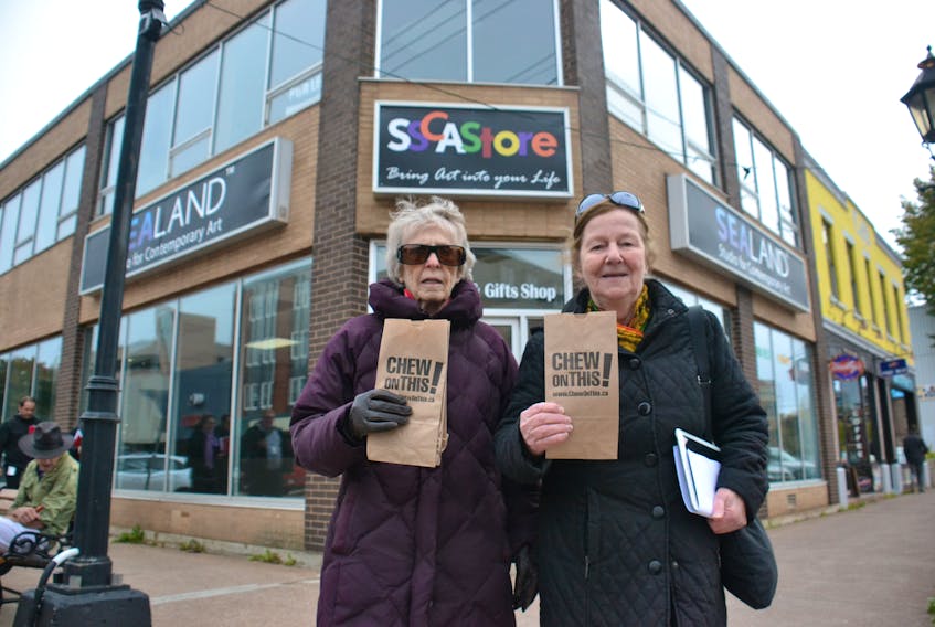 Wanda MacDonald, left, and Mary Boyd hand out bags, replete with Halloween candy and pamphlets, to lunch-hour pedestrians on Kent Street in Charlottetown on Wednesday. Activists are attempting to raise awareness about what they believe are inadequate anti-poverty policies from the Trudeau Liberals.