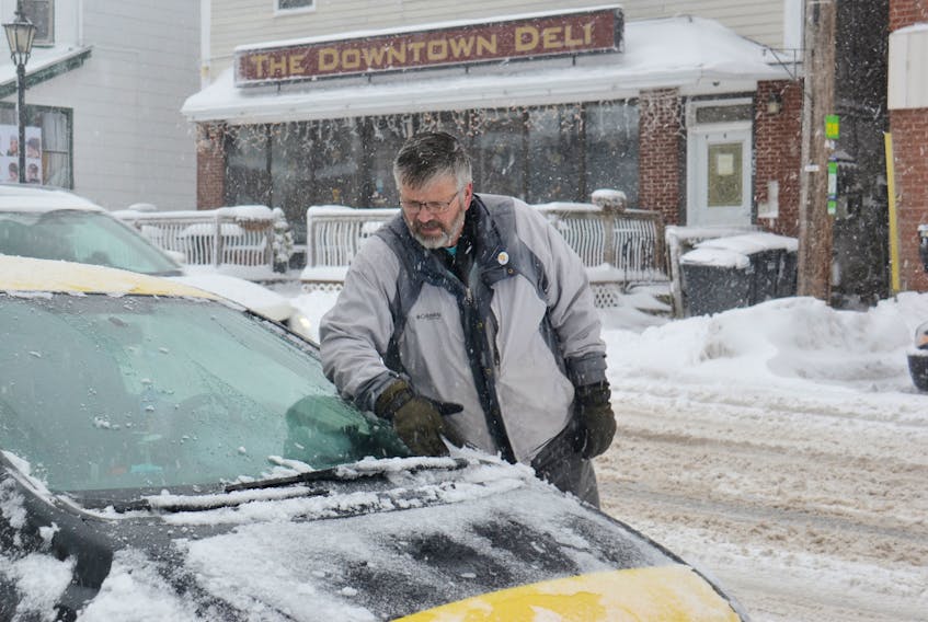 Michael MacIsaac, property manager of Confederation Capital Property Management, cleans off a car Tuesday, Dec. 18, 2018, in Charlottetown.