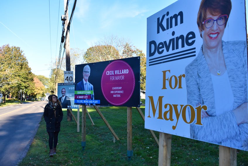 A woman walks by a row of election signs for several candidates in the 2018 municipal election in Charlottetown.