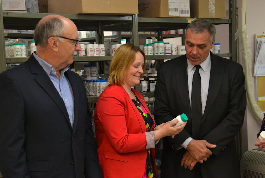 David Hilchey of the Canadian National Institute for the Blind, Jayna Stokes, Manager of Support Services for the Canadian Cancer Society, Health and Wellness Minister Robert Mitchell examine the label of medication at an announcement on Wednesday morning.