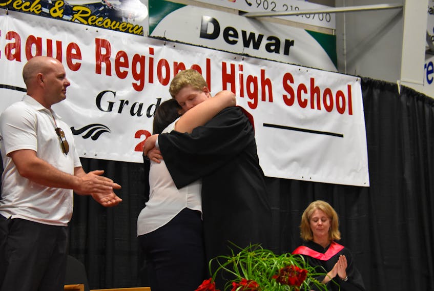 Jacob MacEachern hugs Brodie McCarthy’s mother, Lisa McCarthy, as he accepts the first Brodie McCarthy Memorial Leadership Scholarship on June 21 at the Cavendish Farms Wellness Centre. It was presented at Montague Regional High School’s 2018 graduation. Looking on is Brodie’s father, David McCarthy.