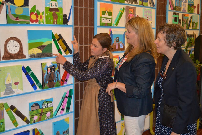 Rylee Lyons, left, a Grade 5 student at L.M. Montgomery Elementary School, shows Kate Macdonald Butler, centre, granddaughter of Lucy Maud Montgomery, and Elizabeth Epperly, co-founder of the L.M. Montgomery Institute at UPEI, some of the paintings students at the school did to celebrate Montgomery’s work. The paintings are part of an Art Smarts project at the school to coincide with the 25th anniversary of the institute at UPEI.