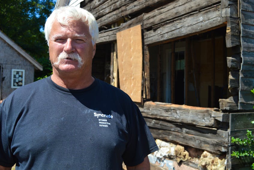 Ray Campbell, who owns a log home on Hillsborough Street in Charlottetown, stands by a part of the structure he took down before the city filed a court injunction ordering him to stop. He and the city now have 10 days to come to a resolution on the matter.