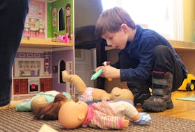 Owen Arsenault, 4, plays with some of the dolls at the CHANCES office in Charlottetown Tuesday morning.