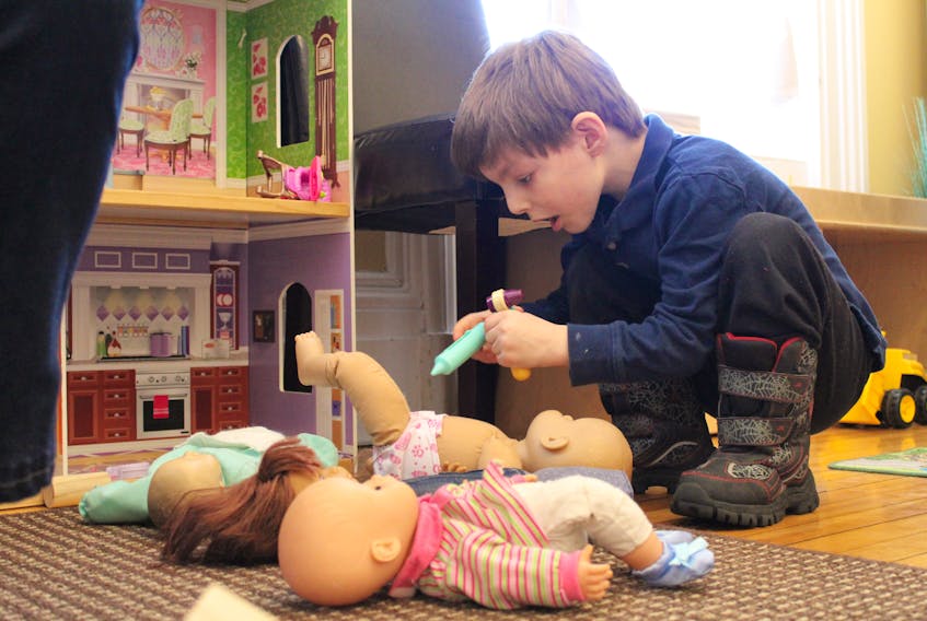 Owen Arsenault, 4, plays with some of the dolls at the CHANCES office in Charlottetown Tuesday morning.