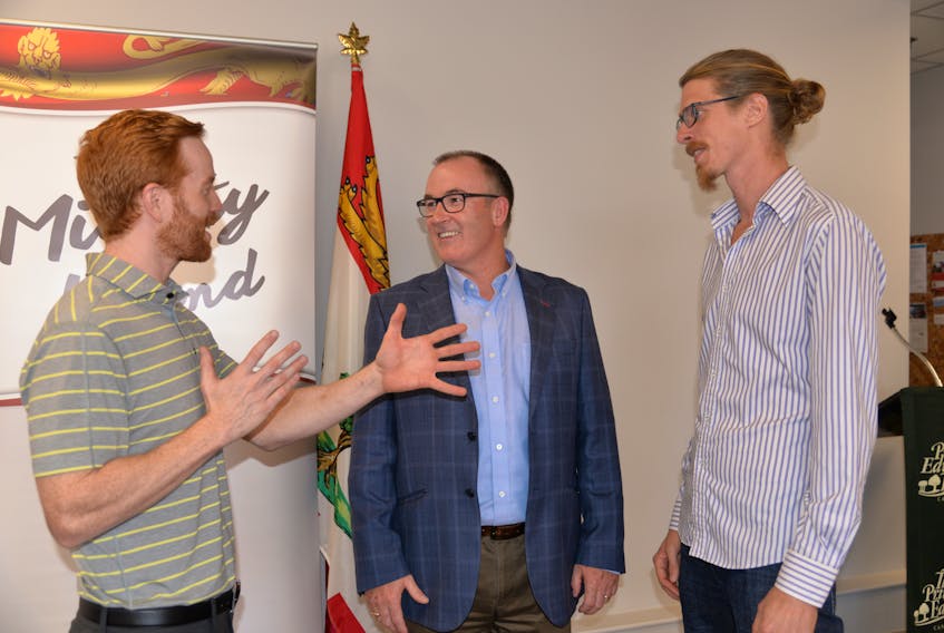James Van Toever, left, and Robert van Waarden, right, of Red Island Cider, talk about the business with Chris Palmer, minister of economic development, at Thursday’s funding announcement.