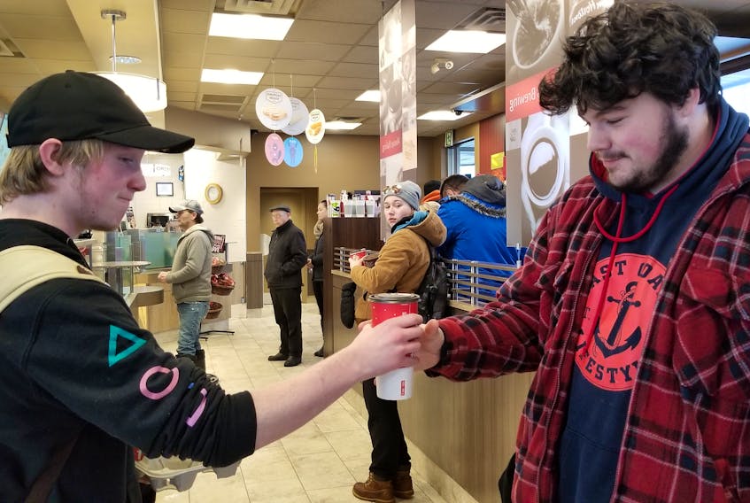 A Tim Hortons customer hands his friend a coffee after the power was restored to the Tim Hortons Grafton Street location in Charlottetown on Thursday morning.