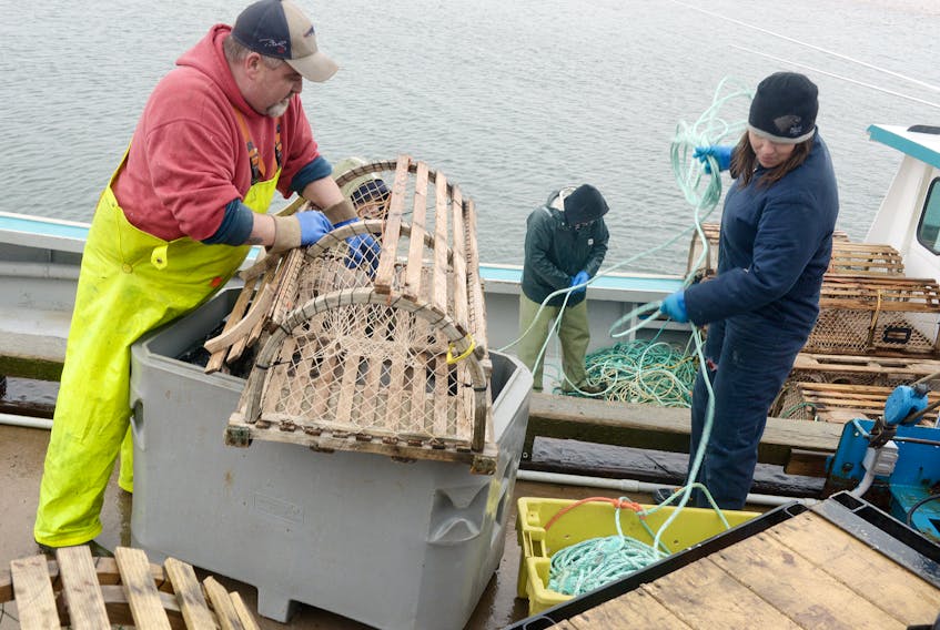 Chris Misener, left, baits a trap while Lorna Doyle-Desroches throws some rope down onto the boat Sneak Preview while preparing for P.E.I.’s spring lobster fishery in North Rustico. Fisheries Minister Robert Henderson said the province is working with the P.E.I. Fishermen’s Association to diversify the type of bait used by lobster fishermen.