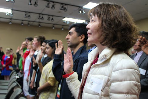 Shao Ching “Nicole” Tseng, right, takes the oath of citizenship alongside 28 other new Canadians during a citizenship ceremony at Skmaqn-Port-la-Joye-Fort Amherst on Canada Day.
