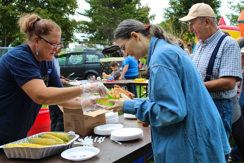 Union of Veterans Affairs Employees member Valerie Quinn, from left, serves up some hotdogs and corn to Demetra and Nabil Saroufim during a Labour Day picnic hosted at Joe Ghiz Memorial Park yesterday. While the barbecue was a fun family event, it also saw union leaders advocate for a universal pharmacare plan.
