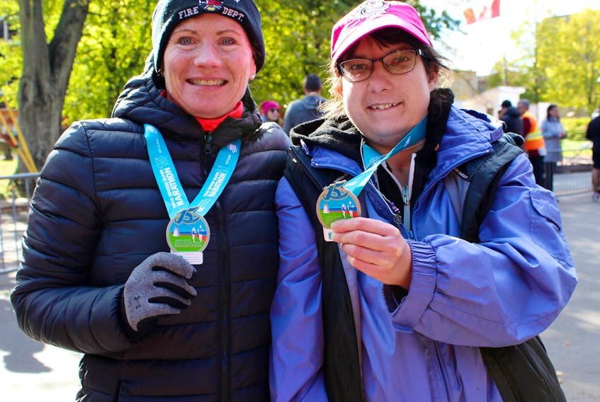 Christi-Joe Snyders-Couchman, right, and her disability support worker Jacquie Lidstone show their participation medals from the 2018 P.E.I. Marathon. Snyders-Couchman finished her first five-kilometre race on Saturday, about three years after suffering an episode of respiratory distress and heart failure.