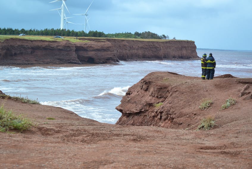 Two Tignish firefighters stand near the water’s edge at North Cape looking for any sign of the two fishermen missing since their boat sank on Tuesday.
