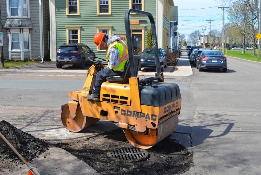 Stephen MacKinnon with Charlottetown’s public works department flattens asphalt around one of the catch basins on Pownal Street on Thursday. City crews and a private contractor will soon begin the major work of paving close to 40 streets across the capital after a harsh winter where various freeze-thaw cycles left many roads in various states of disrepair.