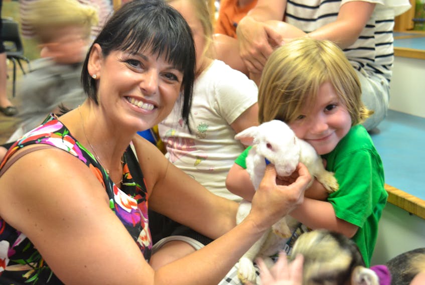 Flory Sanderson of Island Hill Farm poses with Charlie Howett and a bunny rabbit at the Confederation Centre Public Library. Sanderson lead a story-time reading, complete with baby goats and bunnies, on Thursday morning.