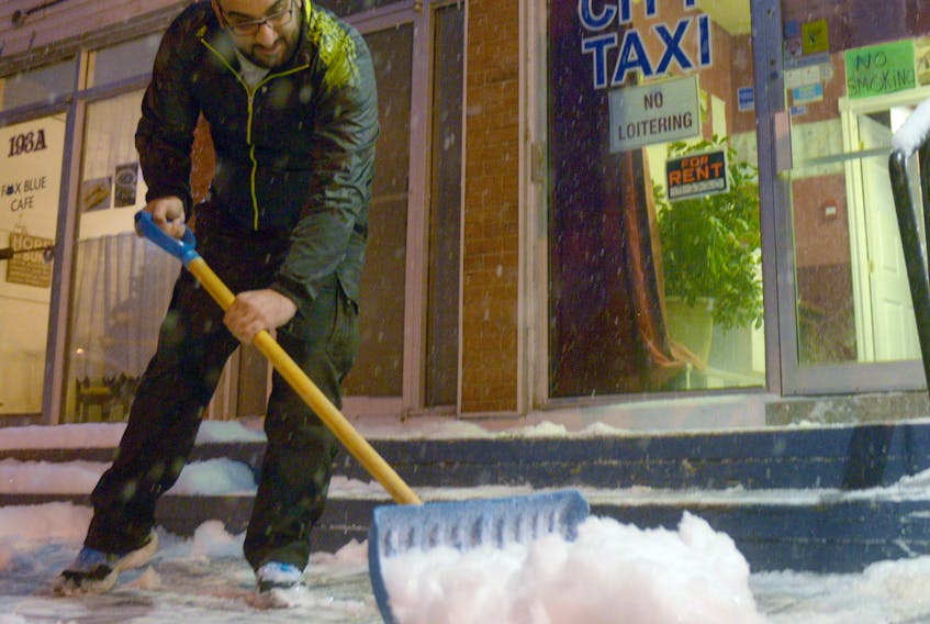 City Taxi driver Ali Baba clears some snow from the deck of the Charlottetown business Wednesday night. Much of the province saw significant snowfall throughout the afternoon and evening, with a snowfall warning in place for Kings and Queens County. Prince County saw a special weather statement.