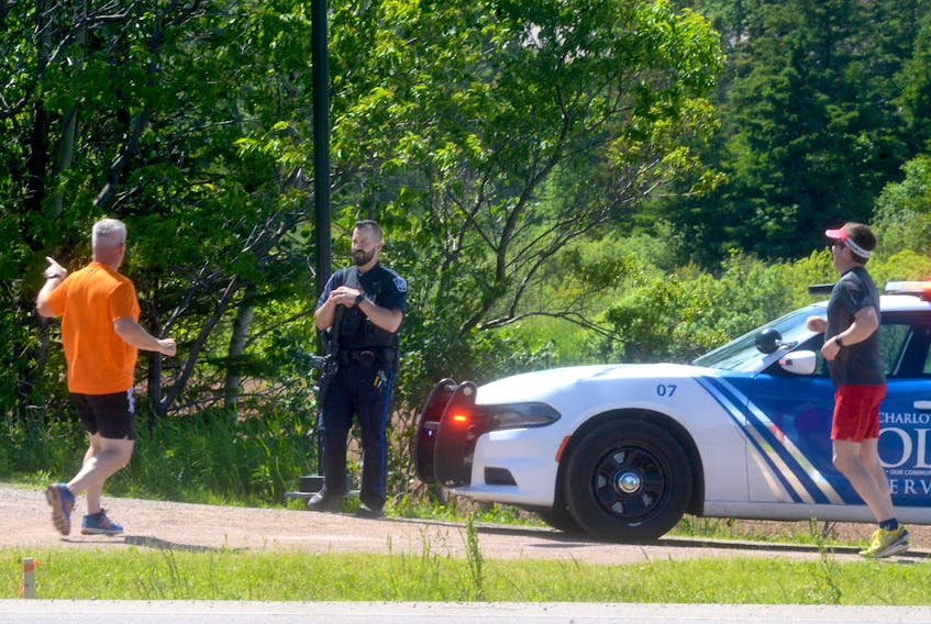 A Charlottetown police officer with a carbine rifle advises two joggers Monday afternoon of a closure at the Confederation Trail. Police blocked off a section of the trail near the bypass highway after hearing a report of a man with a firearm.