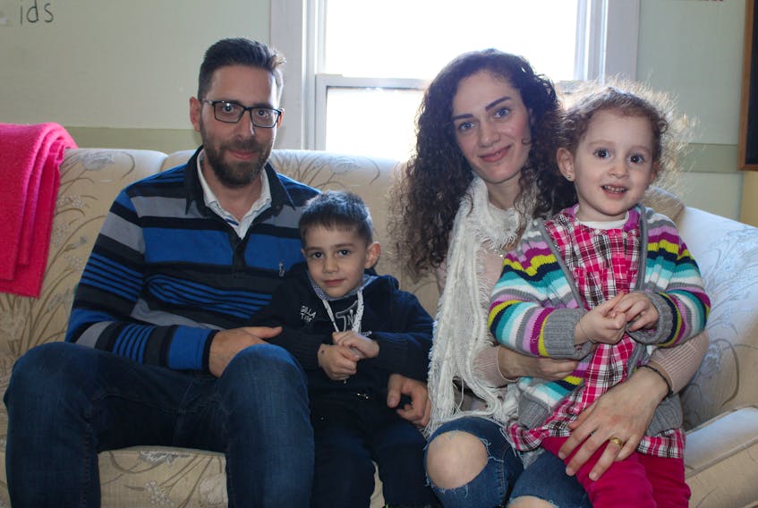 George Nakhleh, left, and Daisy Hamwi hold their two children Mark Nakhleh and Lutchina Hamwi during a potluck at Charlottetown’s Central Christian Church Sunday. The Syrian couple and their children arrived in Canada Friday following years of being separated due to the war in their home country.