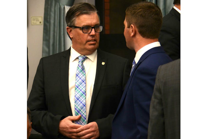 Energy Minister Steven Myers speaks with MLA Cory Deagle prior to question period last week. Myers said the province will be pressing on Maritime Electric to slow its rate increases.