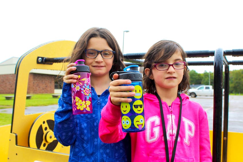 Liv, left, and Abi Bulman, show off their water bottles outside their school, Somerset Elementary School in Kinkora. Staff and students at the school will have to drink bottled water for a while until the Public Schools Branch finds a way to fix the ongoing water quality issues at the school.