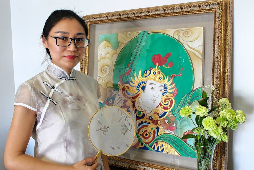 Yan Zhang holds a silk fan at her new Charlottetown gallery, King Deer Art Center. The painting, also by Zhang, is inspired by the Dunhuang art style.