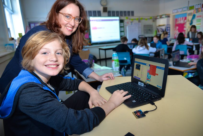 Carron McCabe, program director with Brilliant Labs, discusses coding with student Kai Gillan-Johnson during the Hour of Code event held at West Kent Elementary Wednesday. Students were encouraged to build their coding skills as part of the global event.