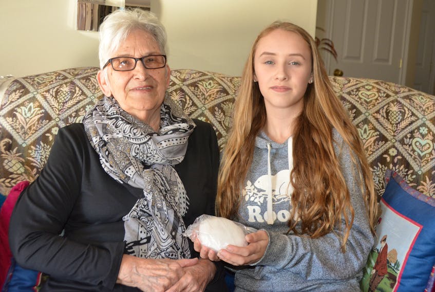 Mae and Alecia Arsenault admire the snowball Mae kept in her freezer for 11 years, a gift from her granddaughter. Ethan Paquet/
