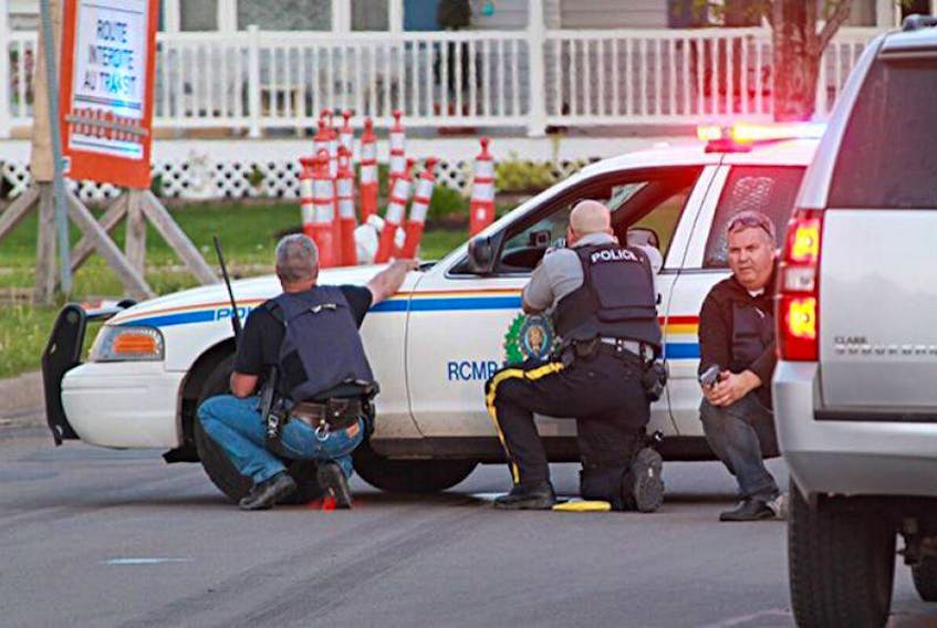 RCMP officers take cover behind their vehicles in Moncton, N.B. on Wednesday June 3, 2014. Three officers were killed in the shootout by a man armed with a rifle, while out-gunned police were largely restricted to handguns.
(The Guardian File Photo)