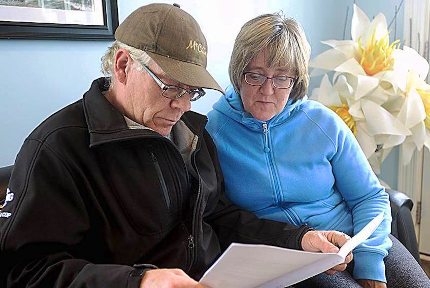 Kent King and Patti King look over a document containing information about the proposed Three Rivers amalgamation and how it would affect residents of Burnt Point and Georgetown Royalty.