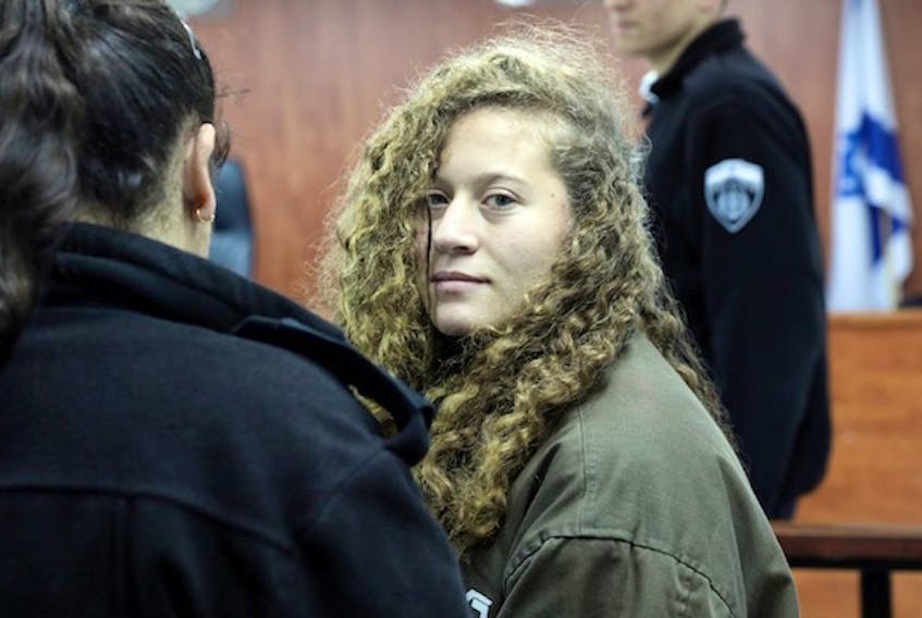 (Ammar Awad / Reuters)

Palestinian teenager Ahed Tamimi enters a military courtroom escorted by Israeli authorities at Ofer Prison, near the West Bank city of Ramallah, on January 1, 2018.