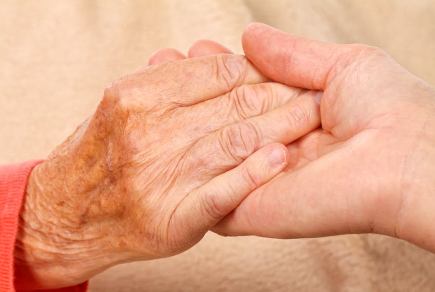 Caregiver holding elderly patients hand at home. www.123rf.com