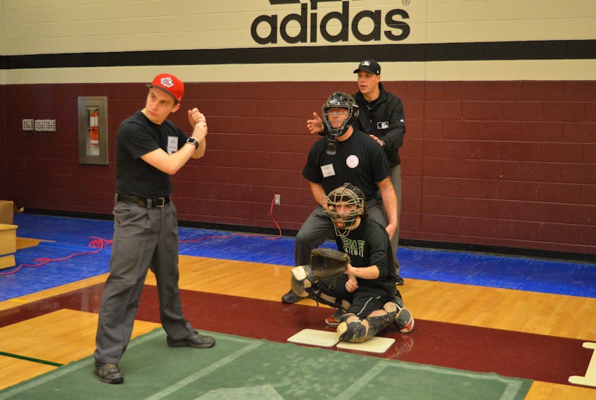 Major League Baseball umpire Stu Scheurwater, right, goes through some drills Saturday at Holland College in Charlottetown during a three-day clinic. From left, Jonathan Schut of Charlottetown acts as the hitter, Patrick Young of Charlottetown is the catcher and Jack McCabe of Miminegash is the umpire.