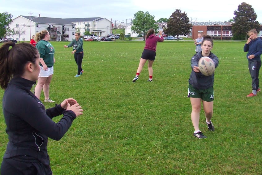 Tessa Hood, centre, of the Charlottetown Rugby Football Club passes a rugby ball to scrum half Bella Walsh while warming up for a recent practice at Charlottetown Rural High School in Charlottetown. Hood and her clubmates host Enfield in the club’s home opener today at Co-op Field.