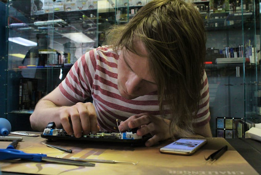 Ben Bain fixes the display on a Wii U game controller at his shop, Geno Games, in Charlottetown.