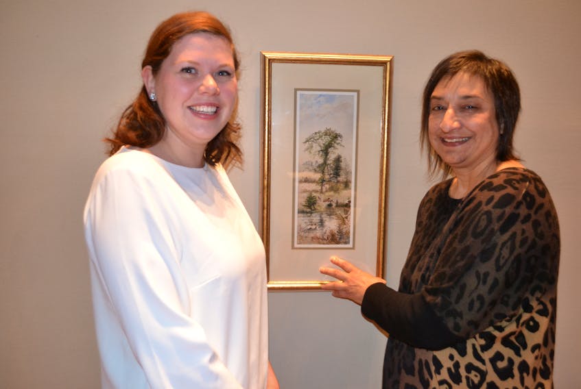 Exhibit co-curator Janet Whytock, left, and Linda Berko, curator of collections with Prince Edward Island Museum and Heritage Foundation, display a painting by Rev. William Stuart. It depicts a man and dog hunting wild fowl at the stream behind the W.J. Montgomery Farm in Port Hill and is one of the artworks to be included in an exhibition of Stuart's work next summer at the Eptek Arts and Culture Centre in Summerside.