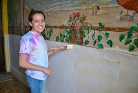 Summer student Mia Fradsham paints the pantry of Glenaladale house in Tracadie Cross.
