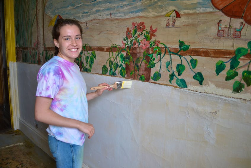 Summer student Mia Fradsham paints the pantry of Glenaladale house in Tracadie Cross.