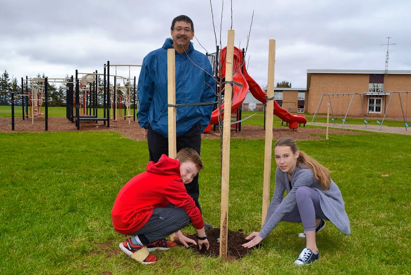 Bloomfield Elementary School students Nolan Cahill and Erica Sweet check up with their teacher, Paul Muise on how well the foraging wall they helped establish on their school’s playground is performing.