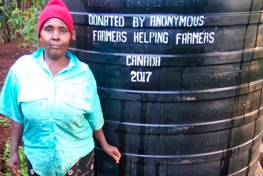 An unidentified Kenyan farm woman stands in front of a water storage tank, sponsored by Farmers Helping Farmers. A fundraising barbecue is Aug. 11 at the Harrington Research Station in support the organization’s work in Kenya.