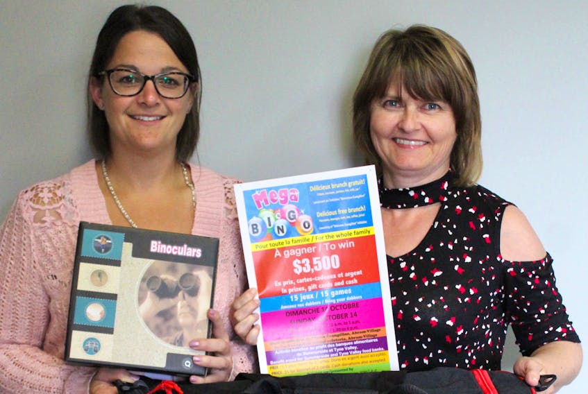 Two of the organizers of the family benefit Mega-Bingo, Amy Richard, left, and Velma Robichaud, display a few of the more than $3,500 worth of prizes that will be won during the Oct. 14 event in Abram-Village.